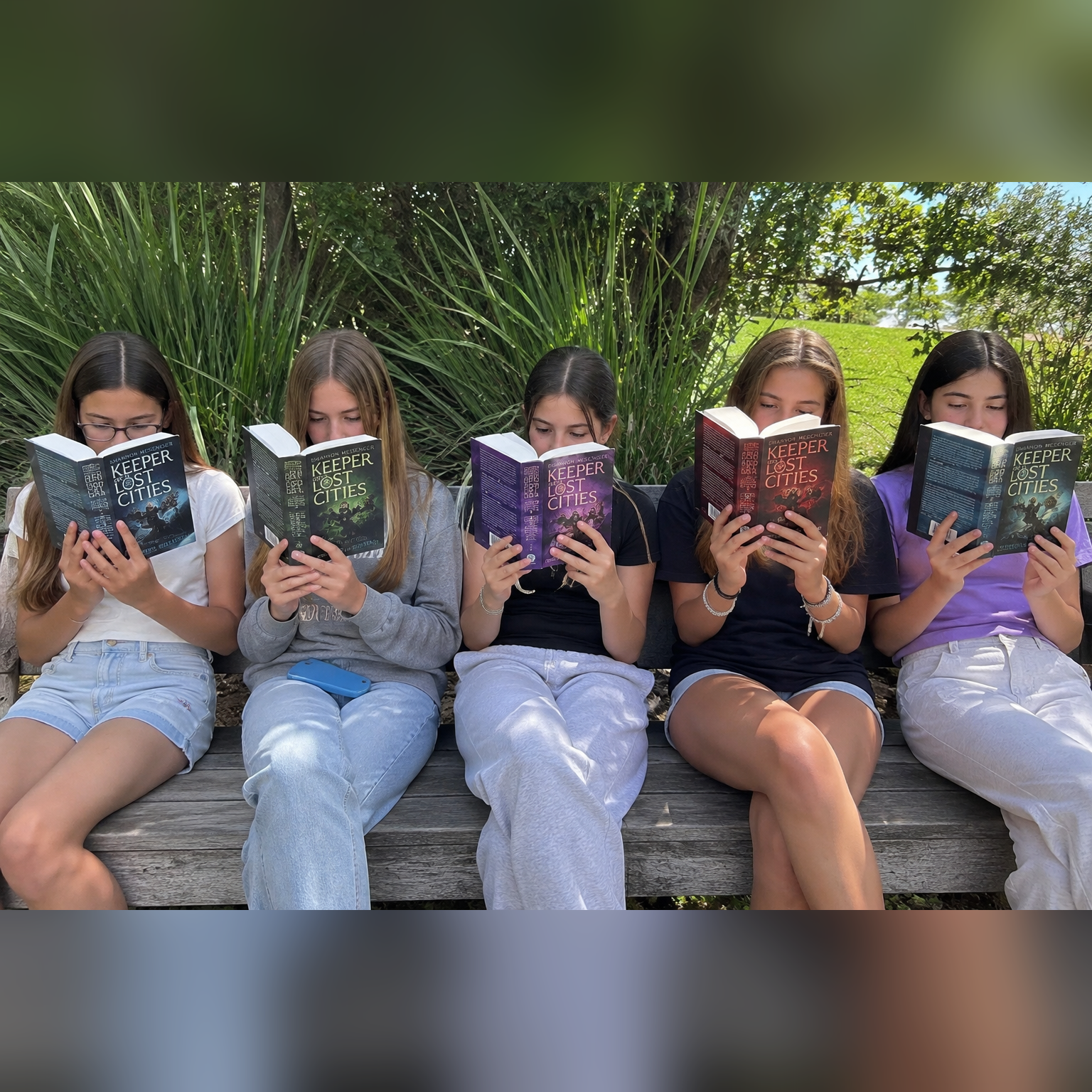 Five girls reading Keeper of the Lost Cities together outdoors